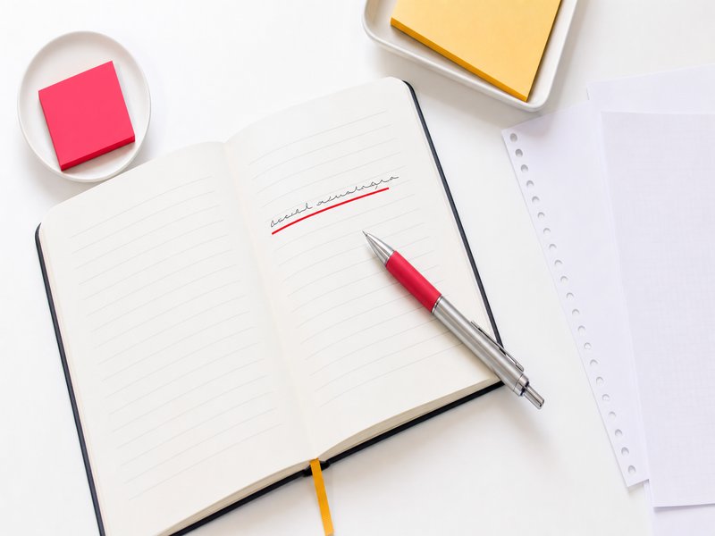 Un carnet de notes ouvert avec une phrase soulignée et un stylo posé dessus, illustration éditoriale sur la reformulation d'une demande